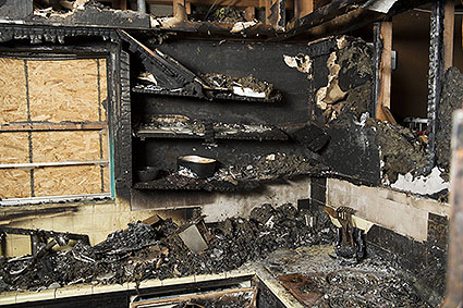 blackened fire damaged cabinets and countertops covered in ash and coal after a fire